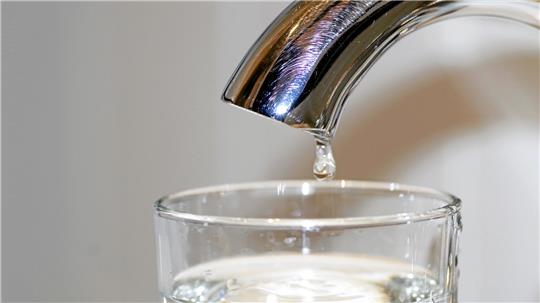 Wasser tropft aus einem Wasserhahn.