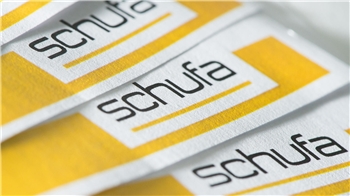 Mehrere weiße Aufkleber mit dem schwarzen Schriftzug 'schufa' auf gelbem Hintergrund