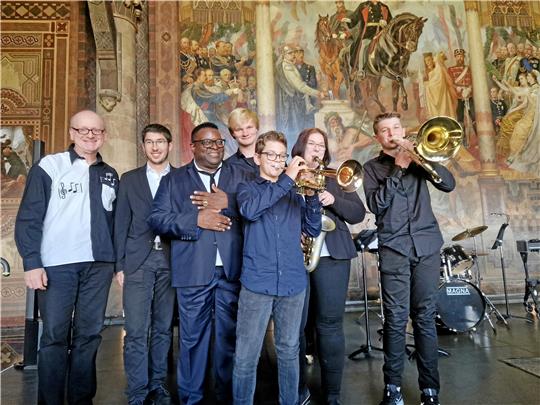 Welche Freude: Isaac Julien (3.v.li.) liebt Musik und fühlte sich durch das Spiel des Future-Jazz-Ensembles der Kreismusikschule unter der Leitung von Jarek Bartoszek (li.) auf besondere Weise willkommen geheißen. Da ging er nach dem Ausklang mit „Isn’t she lovely“ von Stevie Wonder gern zum gemeinsamen Foto zu den Musikern auf die Bühne der Pfalz. Fotos: Sowa/Kempfer