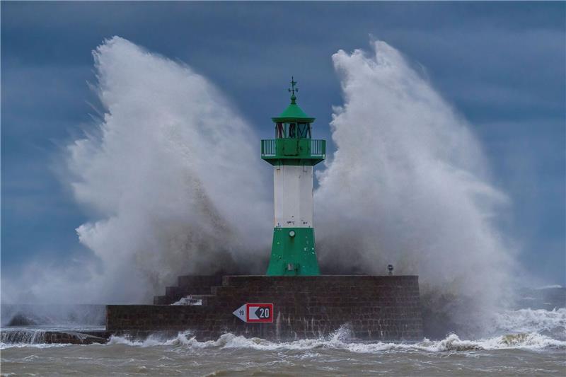 Schwere Sturmflut setzt der Ostsee-Küste zu - Eine Tote Wellen der Ostsee peitschen bei einem schweren Sturmtief an den Leuchtturm auf der Ostmole. Wegen des Sturmtiefs sind an der Ostseeküste Straßen und Uferbereiche vom Hochwasser überschwemmt worden.