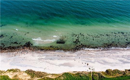 Wellen laufen am Strand der Ostsee am sogenannten Schwedeneck auf den Sand.
