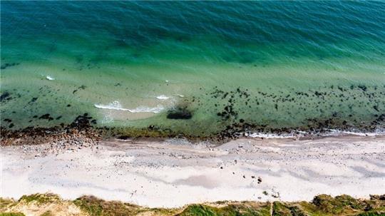Wellen laufen am Strand der Ostsee am sogenannten Schwedeneck auf den Sand.