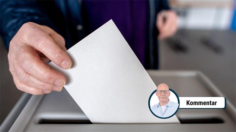 Eine Person wirft einen zusammengefalteten Stimmzettel in eine Wahlurne.