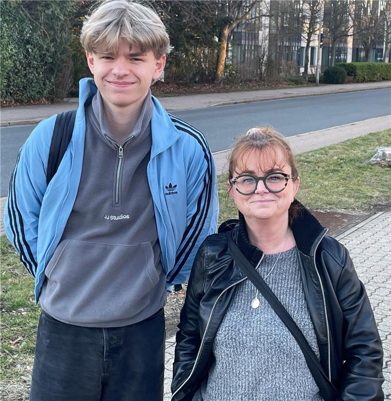 Neue Obergrenze für das Goslarer CvD-Gymnasium Zwei Personen stehen nebeneinander auf einem Gehweg neben einer Straße, eine trägt eine blaue Jacke mit schwarzen Streifen und einen Rucksack, die andere eine schwarze Lederjacke und einen grauen Pullover mit einer Umhängetasche