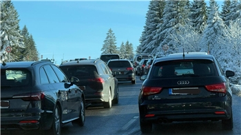 Auf der Straße stehen viele Autos im Stau. 