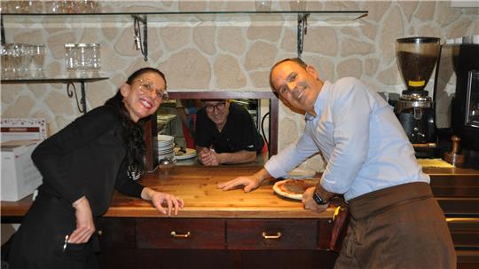 Zwei Männer und eine Frau lehnen über einen Tresen.