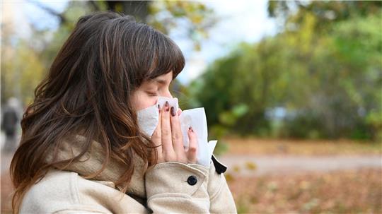 Wer niesen muss, sollte sich von anderen Personen abwenden und ein Taschentuch oder die Armbeuge vor Mund und Nase halten (Symbolbild).