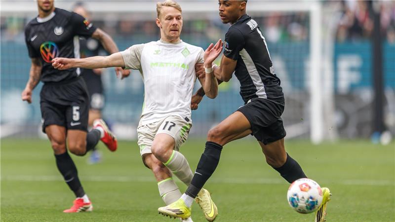 Werders Marco Grüll (l) wird von Wolfsburgs Jeanuel Belocian bedrängt.