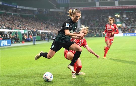 Werders Michaela Brandenburg (l) kämpft gegen Freiburgs Judith Steinert um den Ball.