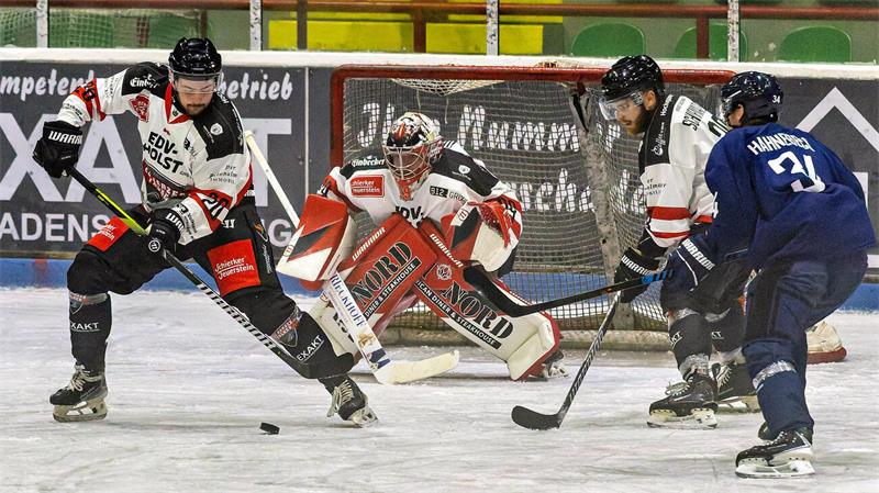 Eishockeyszene mit Torwart und drei Spielern vor dem Tor auf dem Eis