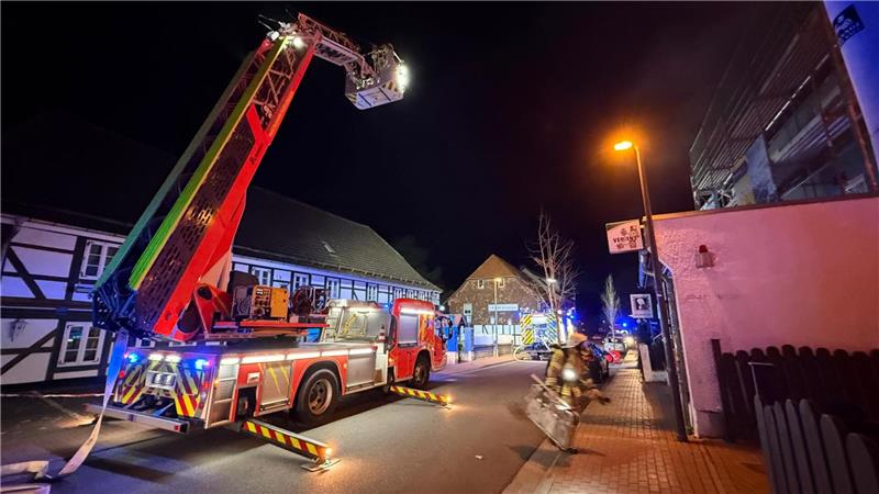 Eine Drehleiter steht ausgefahren auf einer Straße in der Dunkelheit.