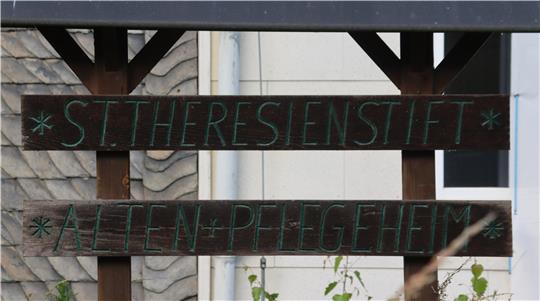 Zwei alte Holztafeln mit der Aufschrift "St. Theresienstift" und "Alten- und Pflegeheim".