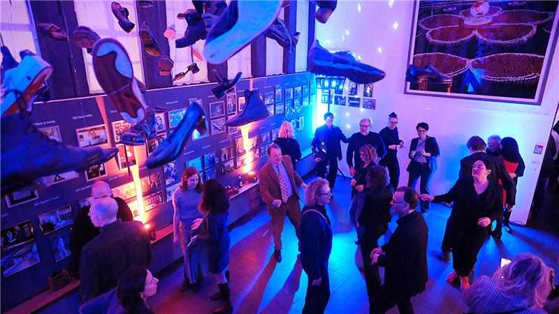 Etwa ein Dutzend Menschen tanzt in blau-violettem Discolicht.