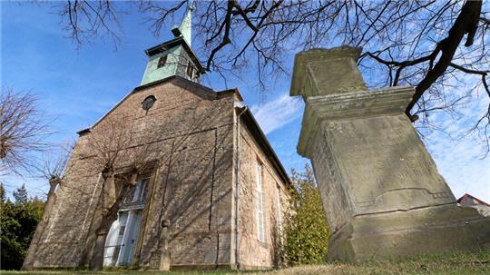 Eine Kirche unter blauem Himmel mit einem Gedenkstein im Vordergrund.
