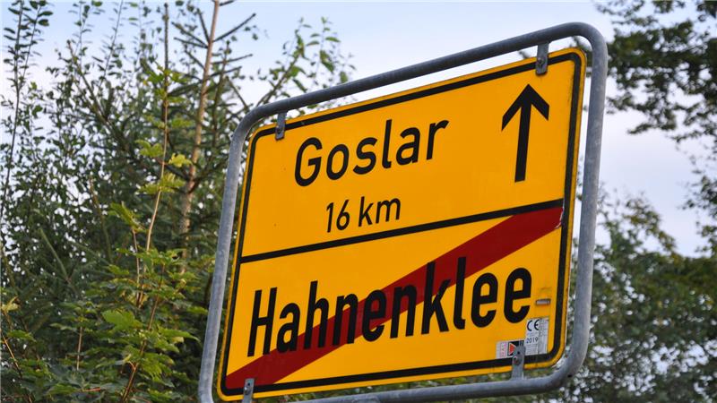 Gelbes Ortsschild mit schwarzer Schrift zeigt Richtung nach Goslar (16 km) und durchgestrichenen Ortsnamen Hahnenklee