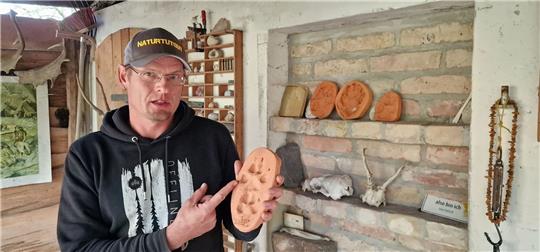 Wildnispädagoge Paul Wernicke zeigt in seiner Wildnisschule in Bad Belzig den Pfotenabdruck eines Wolfes in Ton.