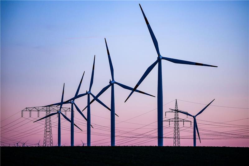 Deutschland wird beim Umbau des Strommarkts überholt Windkraftanlagen und Hochspannungsleitungen sind vor dem Abendhimmel bei Leuna zu sehen.