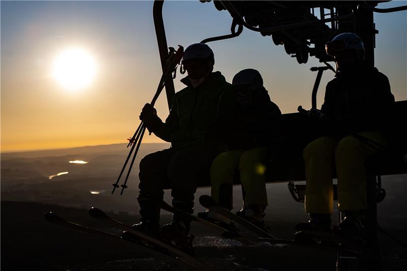 Skifahren im Harz: Ticketpreise sollen nur leicht steigen Wintersportler sitzen bei Sonnenaufgang im Sessellift.