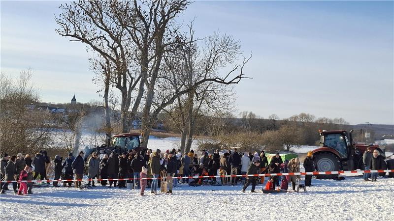 Eine große Zuschauergruppe verfolgt vom Pistenrand das Geschehen.