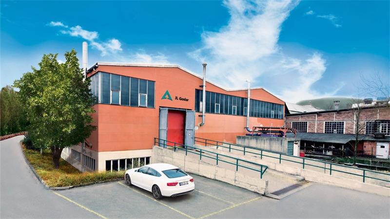 Rotes Industriegebäude mit großen Fenstern, Rampe und weißem Auto auf Parkplatz davor