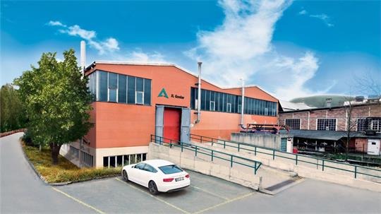 Rotes Industriegebäude mit großen Fenstern, Rampe und weißem Auto auf Parkplatz davor