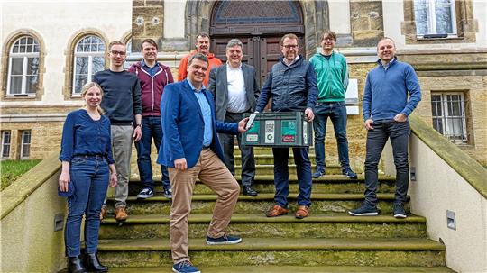 Wirtschaftsstaatssekretär Stefan Muhle hält eine Elektrogeräte-Sammelkiste in der Hand. Mit ihm freuen sich Landrat Dr. Alexander Saipa (vorn), TU-Präsident Professor Joachim Schachtner (4. v. re.) und Professor Andreas Rausch (4. v. li.) vom „Center for Digital Technologies“ mit anderen Projektbeteiligten über das Pilotvorhaben.  Foto: Privat