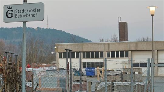 Gelände mit Zaun, Laterne und Schild 'Stadt Goslar Betriebshof' vor bewaldetem Hügel im Hintergrund