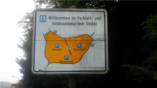 Straßenschild mit orangefarbener Karte und blauen Parksymbolen für Altstadt, Zentrum und Kaiserpfalz im Parkleit- und Hotelroutensystem Goslar.