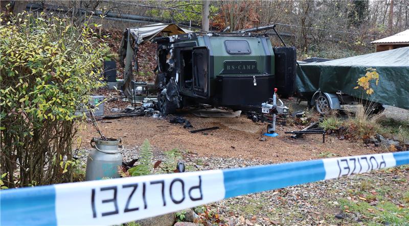 Polizeiabsperrung vor einem verbrannten Anhänger