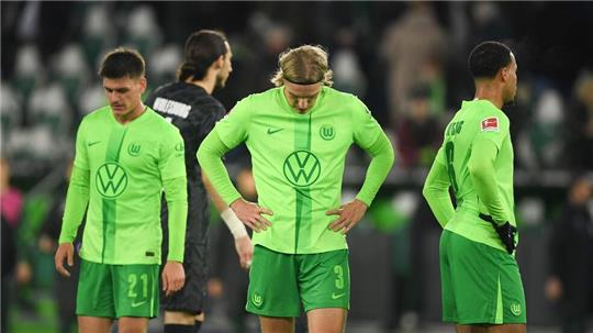 Wolfsburgs Sebastiaan Bornauw (M), Joakim Mæhle (l) und Aster Vranckx ärgern sich über den verspielten Sieg. 