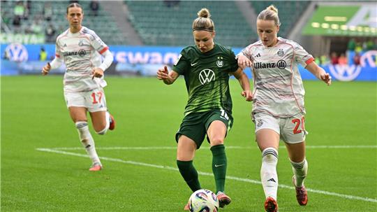 Wolfsburgs Svenja Huth (M) im Zweikampf mit Franziska Kett vom FC Bayern München.