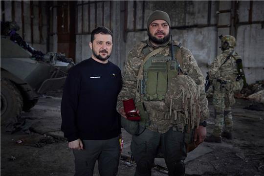 Wolodymyr Selenskyj steht neben einem Soldat anlässlich einer Verleihungszeremonie in einer Stellung in der Nähe von Bachmut.