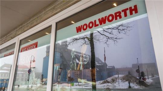 Der Schriftzug „Woolworth“ ist auf einer Fensterscheibe angebracht, im Hintergrund spiegelt sich die Clausthaler Marktkirche.