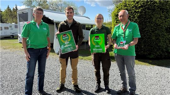 Das Foto zeigt vier Menschen, die teilweise mit Pokalen auf einem Campingplatz stehen.
