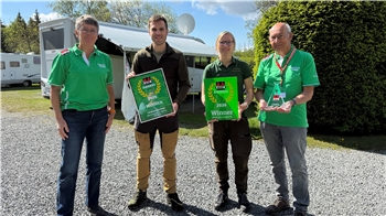 Das Foto zeigt vier Menschen, die teilweise mit Pokalen auf einem Campingplatz stehen.