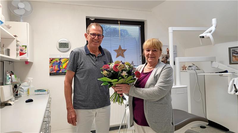 Zahnarzt Johannes-Josef Engelke überreicht Jutta Ehrenberg einen Blumenstrauß zum Abschied. Foto: Skuza
