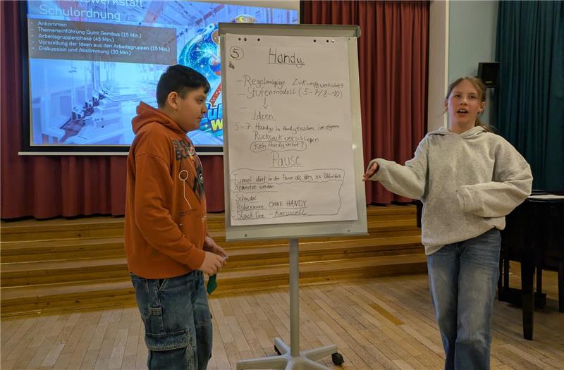 Das Foto zeigt zwei Schüler vor einer beschrifteten Leinwand.