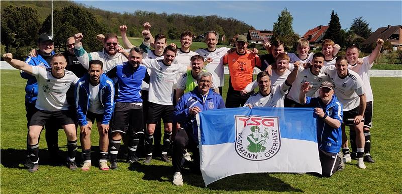 Fußballmannschaft auf dem Spielfeld jubelnd mit einer Fahne der TSG Wildemann