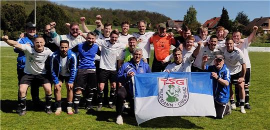Fußballmannschaft auf dem Spielfeld jubelnd mit einer Fahne der TSG Wildemann