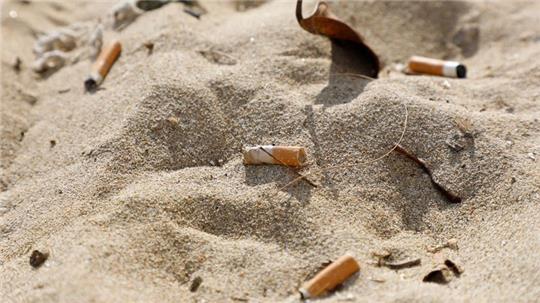 Zigarettenstummel liegen im Sand am Strand von Arenal. Foto: Clara Margais/dpa/Symbolbild