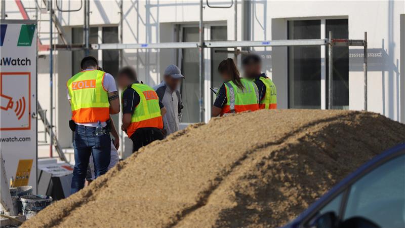 Zoll-Mitarbeiter kontrollieren Beschäftigte auf einer Baustelle.