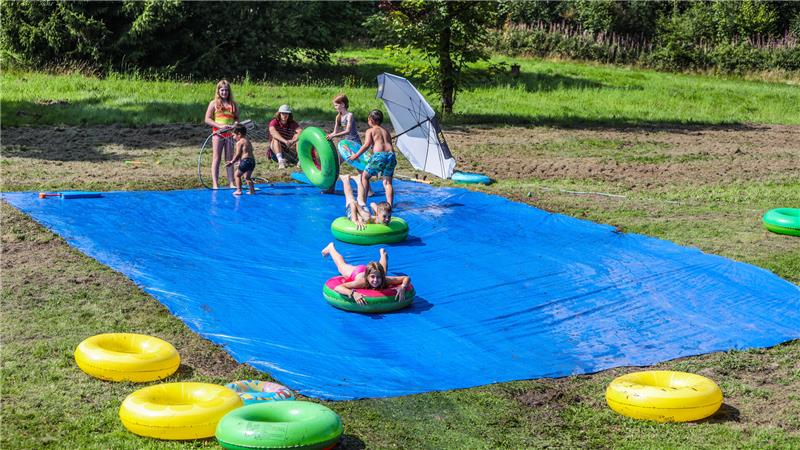 Von ein paar Kids zum Mega-Event: Fest in Festenburg bricht Rekord Zu den Attraktionen des Kinderfestes gehört bei den hohen Temperaturen die Wasserrutsche, auf der die Kinder mit Reifen eine feuchte Plane hinab sausen.