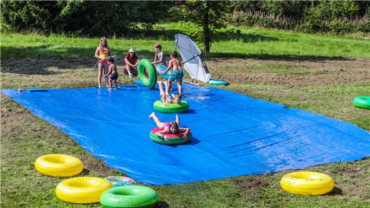 Zu den Attraktionen des Kinderfestes gehört bei den hohen Temperaturen die Wasserrutsche, auf der die Kinder mit Reifen eine feuchte Plane hinab sausen.