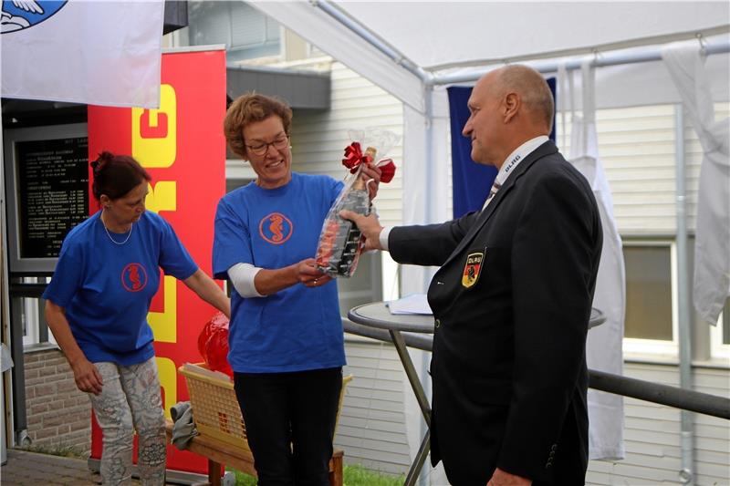 Zum Auftakt überreicht der Bezirksleiter Helmut Fichtner an die Ortsvereinsvorsitzende Cornelia Ehrhardt ein kleines Geschenk zum Jubiläum. Danach wird die Feier im Becken fortgesetzt.