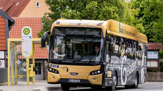 Stadtbus fährt an einer Haltestelle vorbei.
