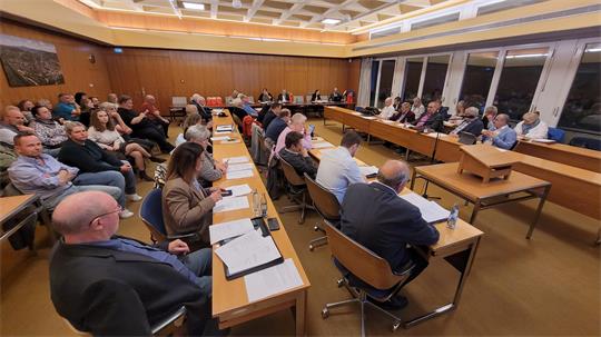 Das Bild zeigt einen Sitzungssaal voller Menschen, die an Tischen und auf Stühlen sitzen.