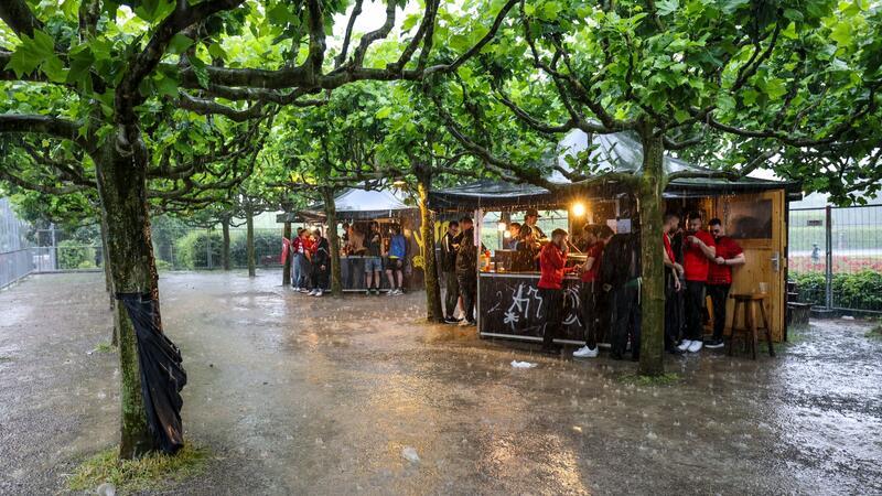 Unwetter in Teilen Deutschlands - Fanzonen betroffen Zumindest ein bisschen Schutz: Fussballfans in Dortmund haben sich beim strömenden Regen an Imbissbuden untergestellt.