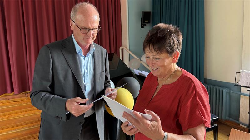 Das Foto zeigt einen Mann, der einer Frau etwas übergibt.