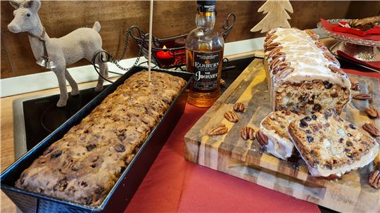 Das Foto zeigt ein Früchtebrot in einer Kastenform und einen Christmas Cake auf Holzbrett auf einem gedeckten Tisch.