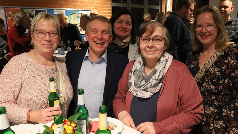 Fünf Personen stehen zusammen an einem Tisch.